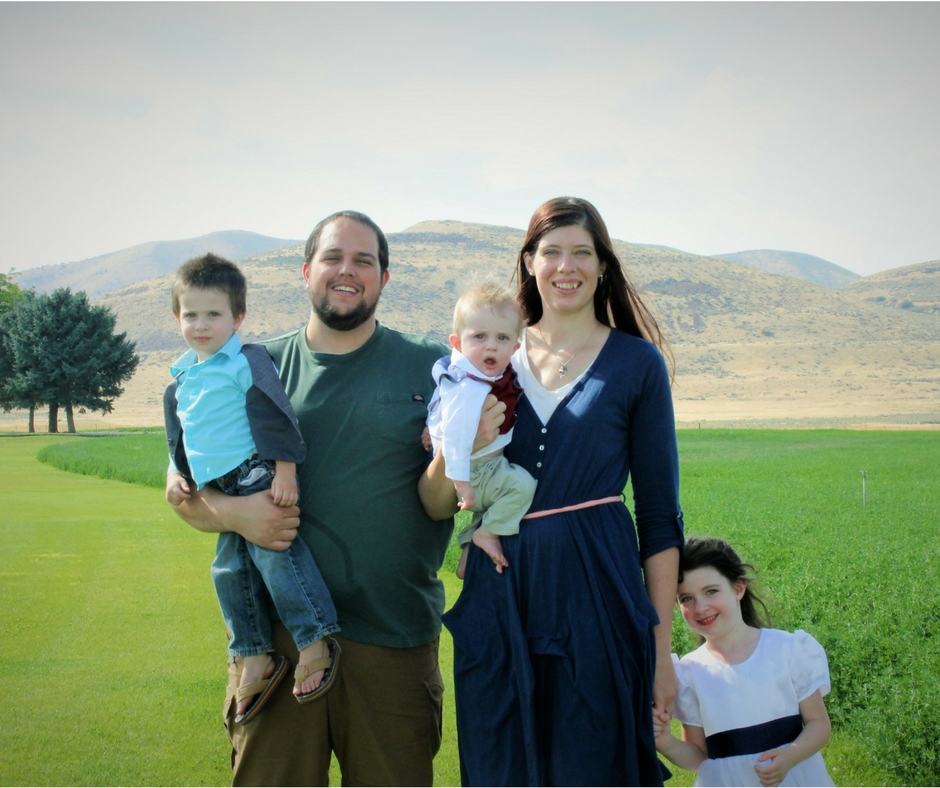 A young family standing in front of the mountains.