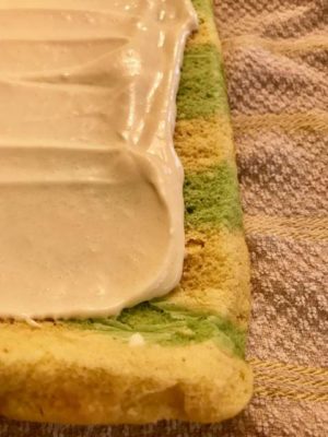 cream cheese frosting on green and vanilla cake roll