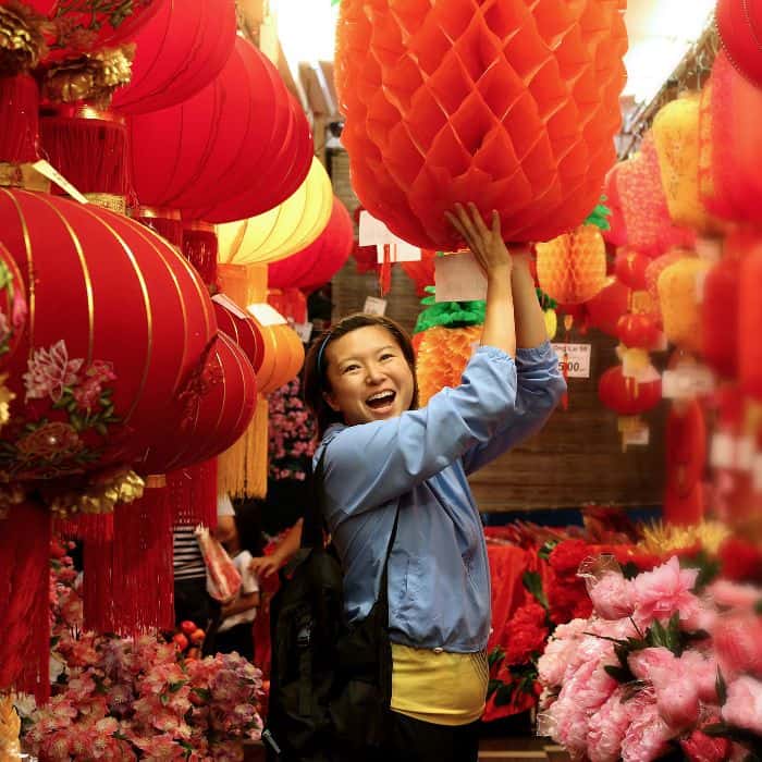 A Chinese woman holding up red lanterns.