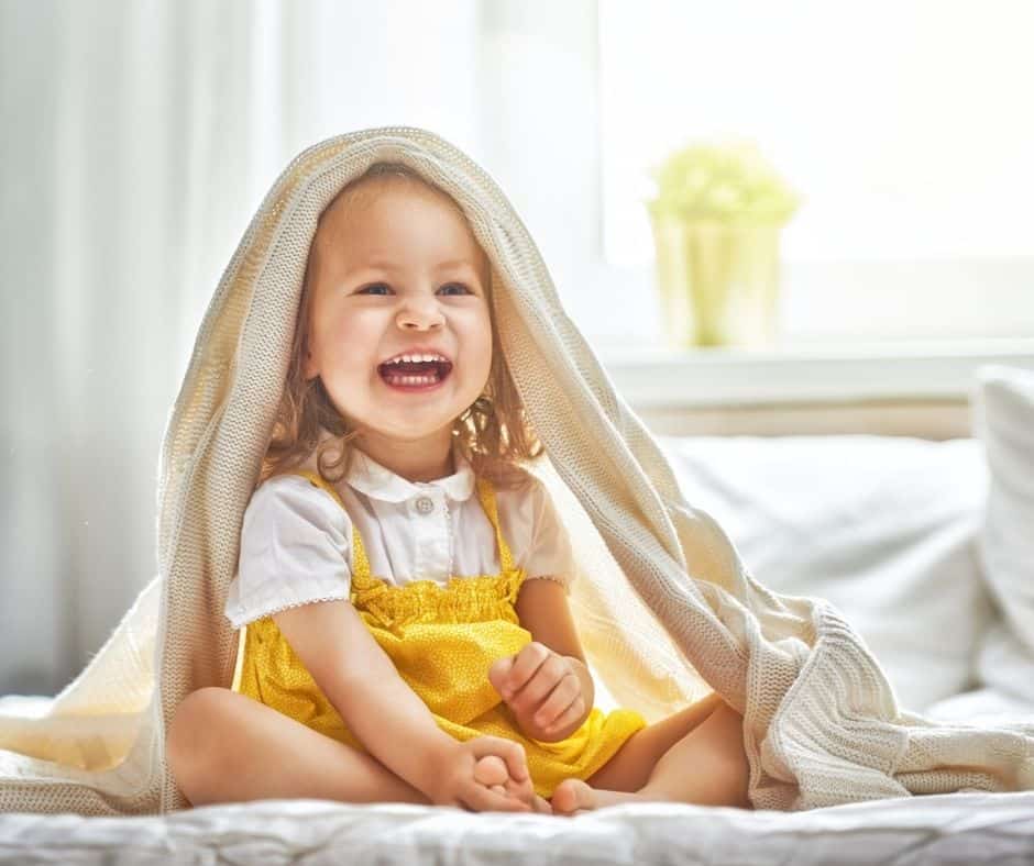 Little girl in bedsheets on bed.