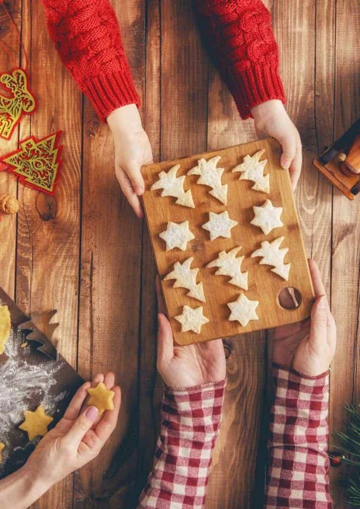 Family baking Christmas cookies together in the same of trees and stars.