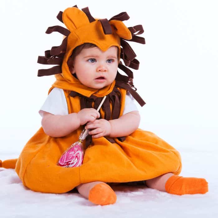 A little baby dressed up in a lion costume.