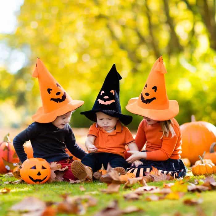 Three little babies dressed in cute pumpkin hats for Halloween.