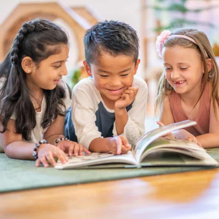 Three kids reading a book together.