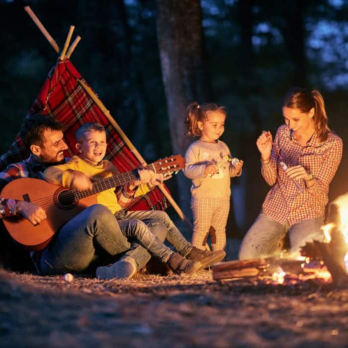 A family camping and sitting by the camp fire.