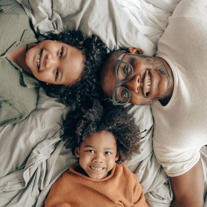 A father and two children are smiling as they spend time together.