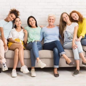 A group of middle aged and older women sitting on a couch together.