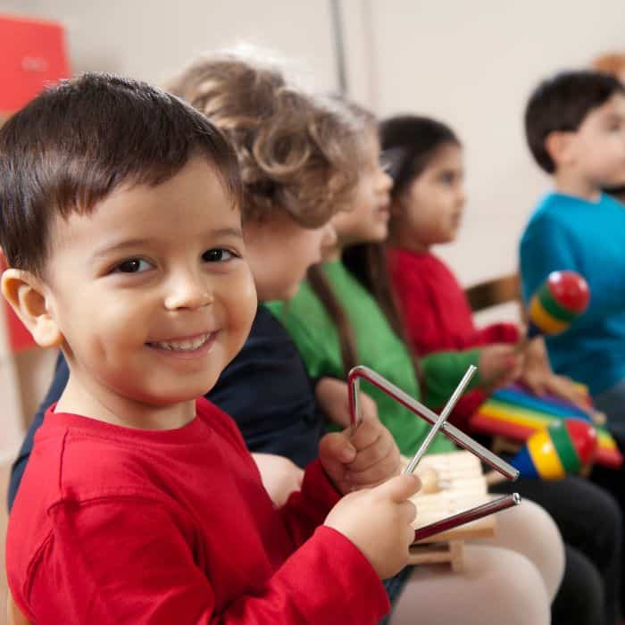 A preschooler in music class playing the triangle. 