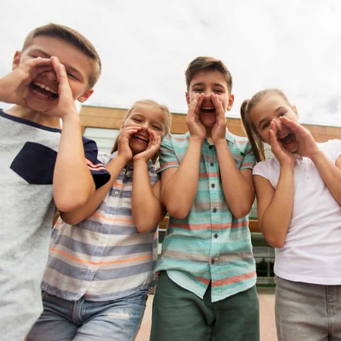 A group of elementary children cupping their hands over their mouths to shout something.