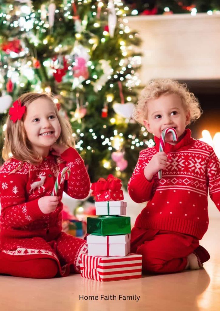 Two children sitting in front of a Christmas tree.