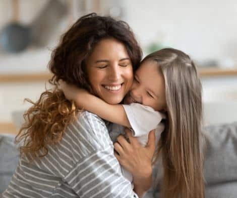 A mother teaching her daughter about gratitude and thankfulness by giving her a hug.
