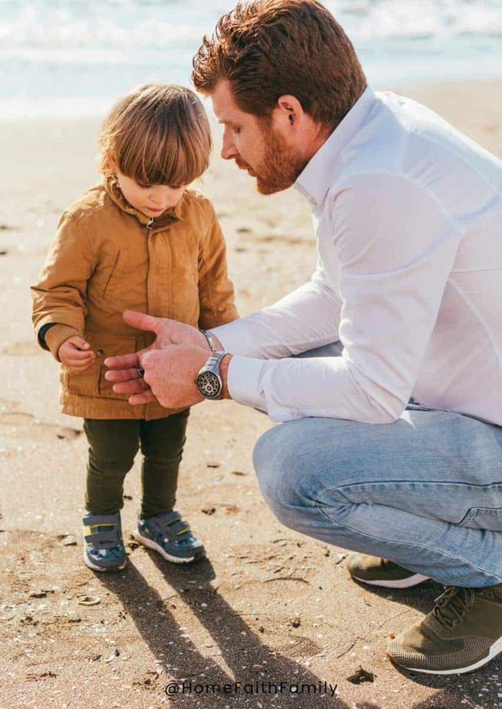 A father kneeling down by his child and teaching his young son.