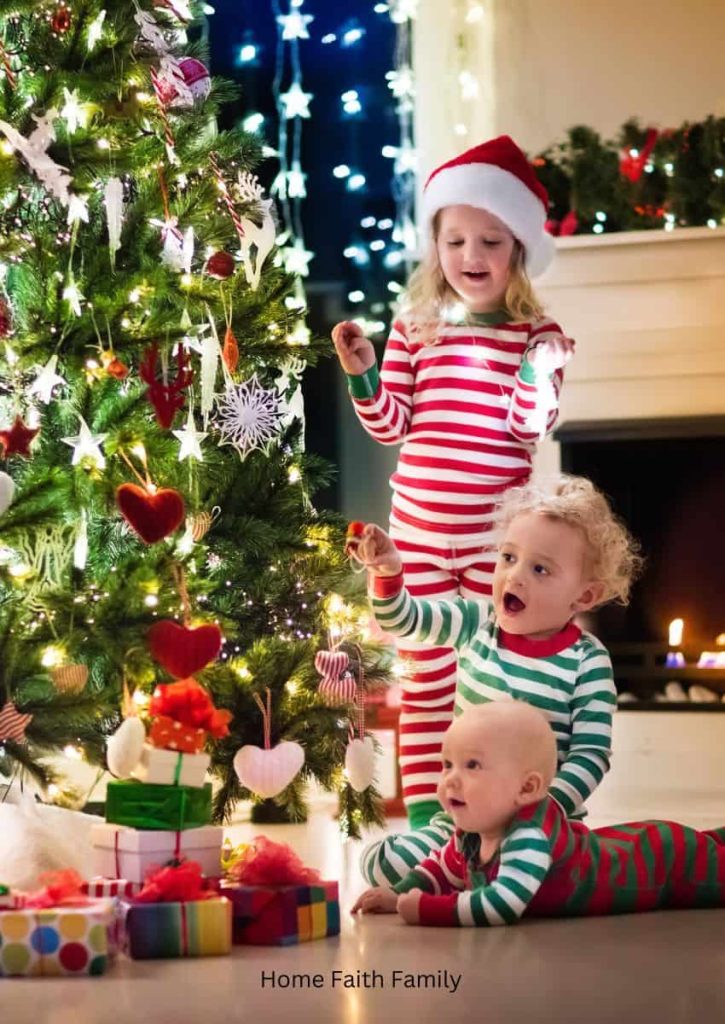 Three small children by the Christmas tree.