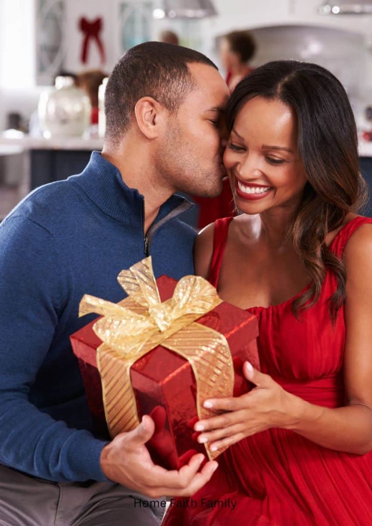 A couple exchanging Christmas gifts and kisses.