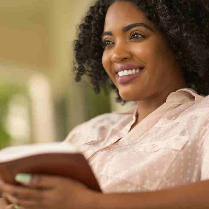 A woman reading her Bible with a smile on her face.