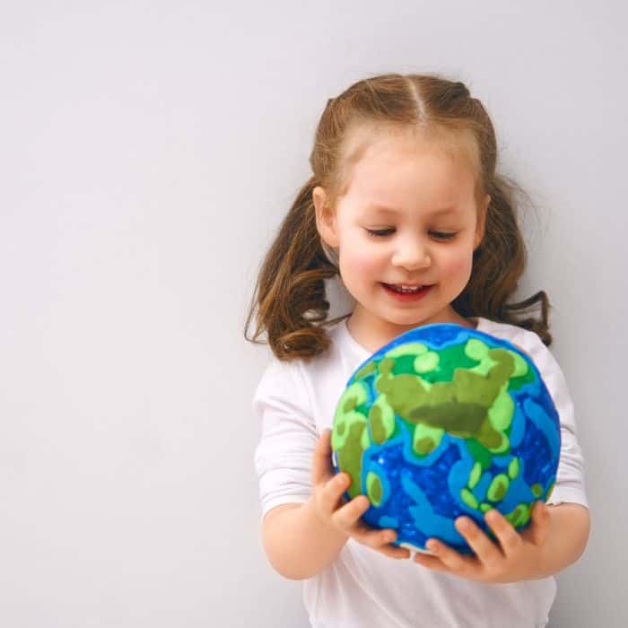 A little girl holding a globe of the planet Earth.