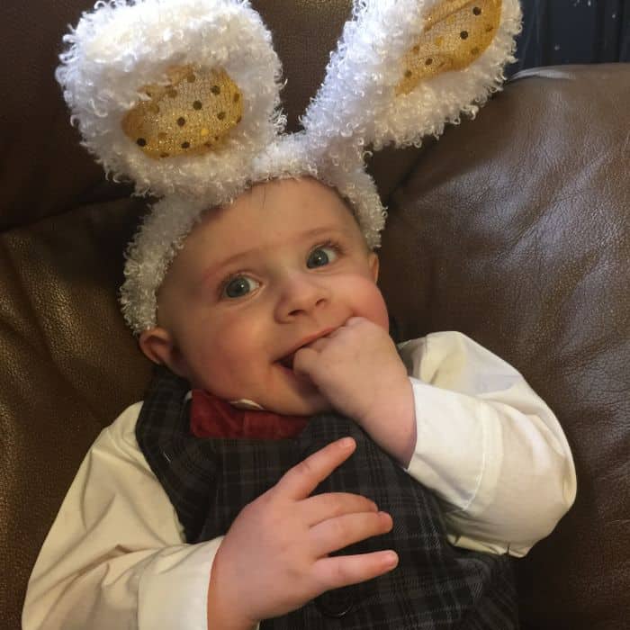 1 year old little boy dressed in an Easter Sunday outfit with Easter bunny ears on his head.