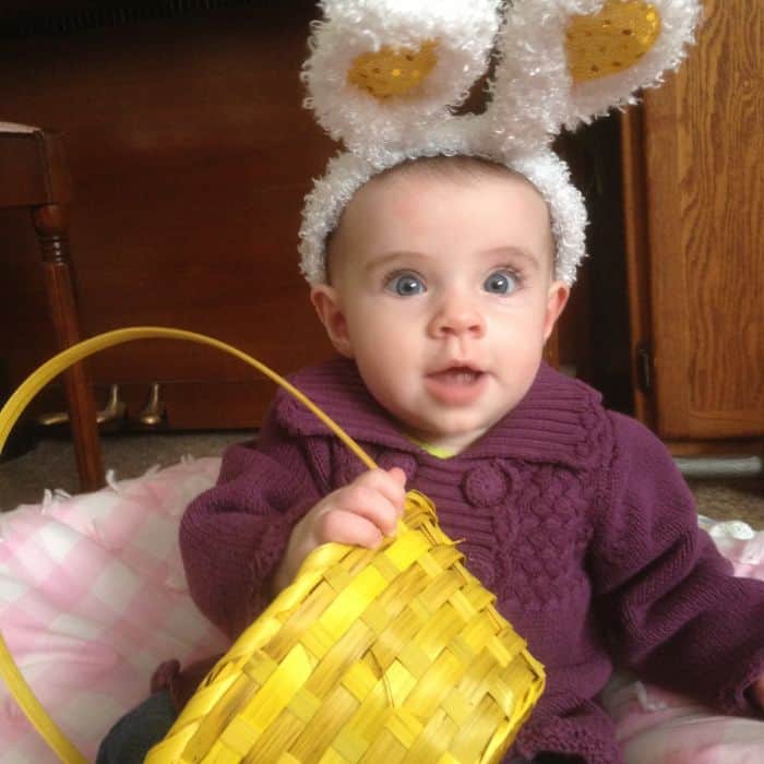 1 year old little girl with Easter bunny ear headband and a yellow Easter basket.