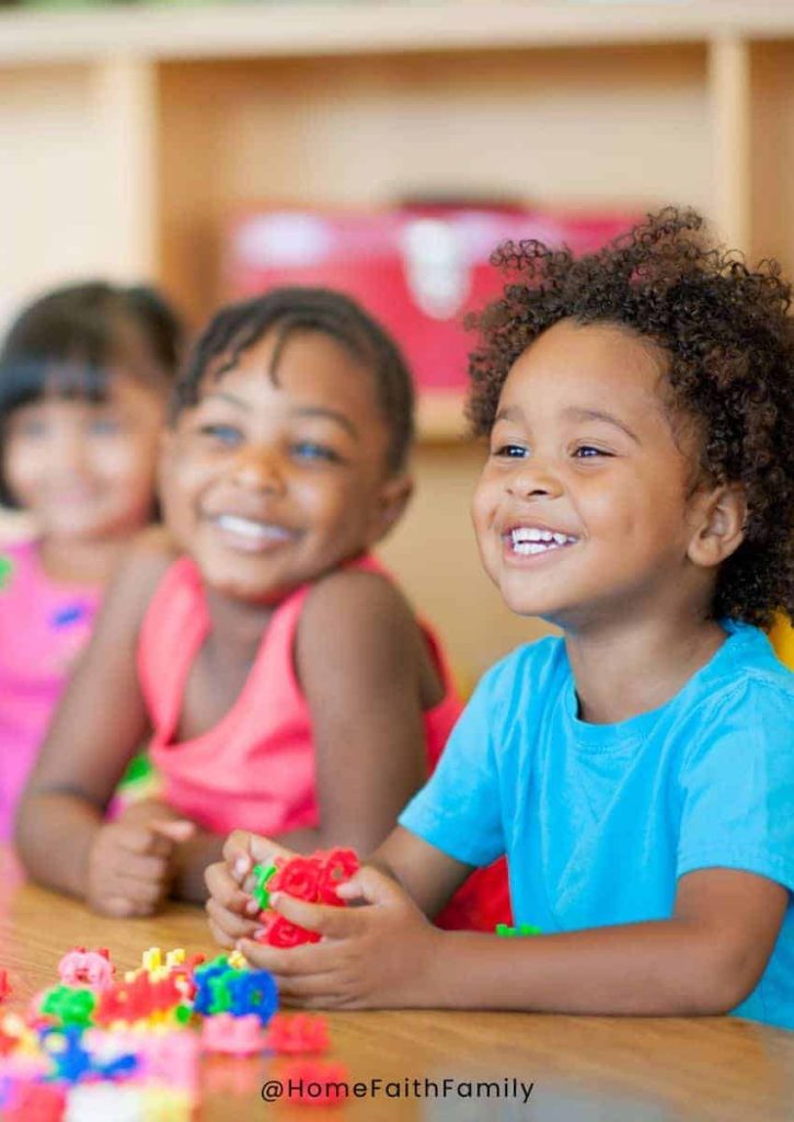 Preschool children sitting at a table playing and laughing.