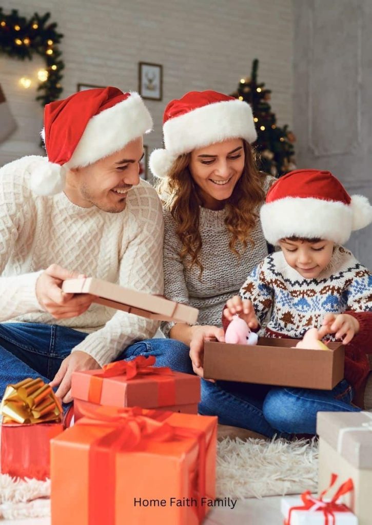 Two parents and small child wearing Christmas hats while surrounded by presents and boxes.