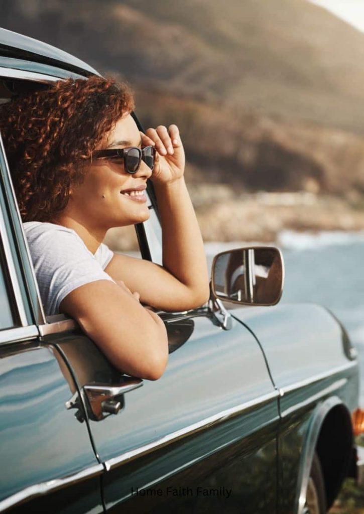 A woman looking out an old sports car with a pair of sunglasses.