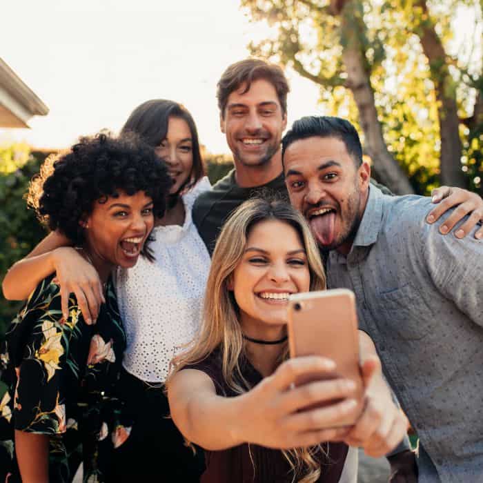 A group of friends taking a picture on a girl's cell phone.