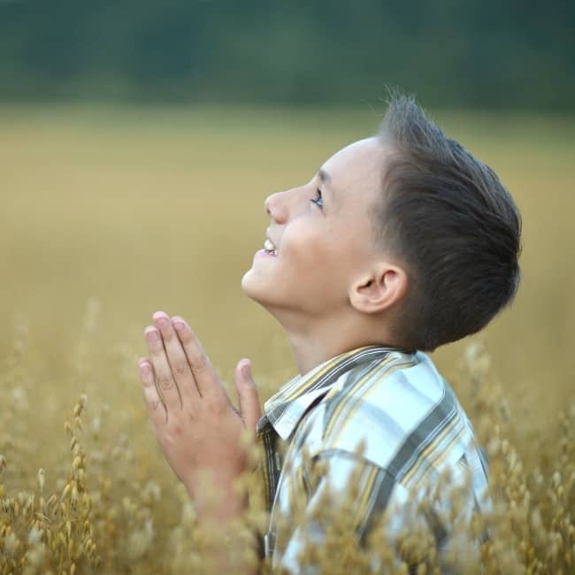 Games for prayer. Boy praying in a field.
