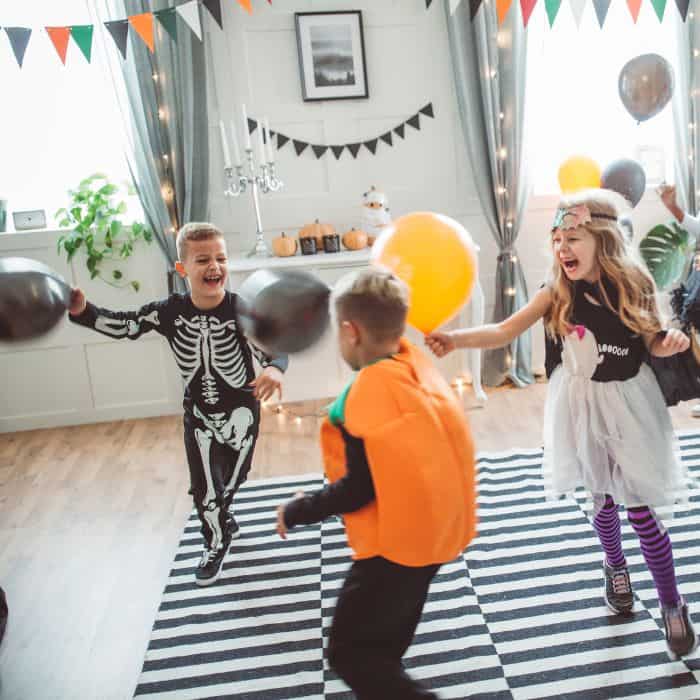 Kids dressed in Halloween costumes dancing in the living room.