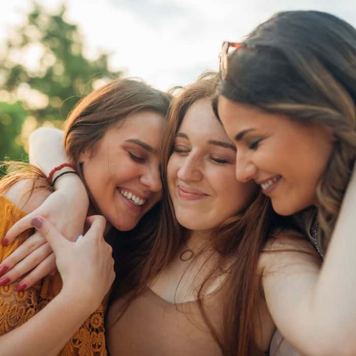 A group of three women hugging and celebrating each other.