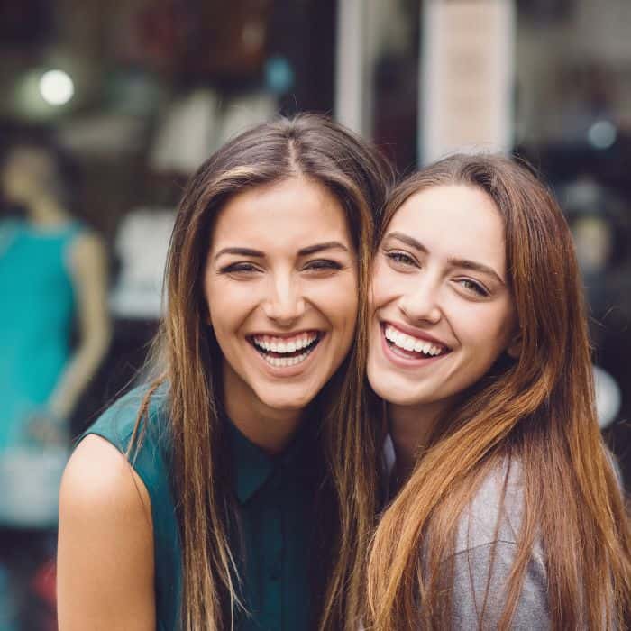 Two women smiling and hugging each other.