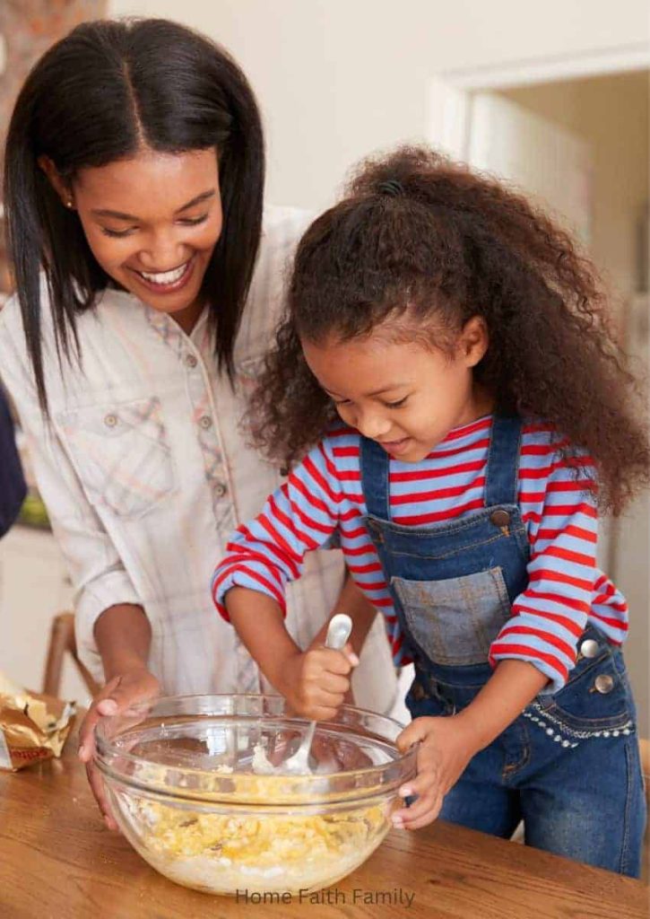 A mother and a daughter stirring a bowl of food together.