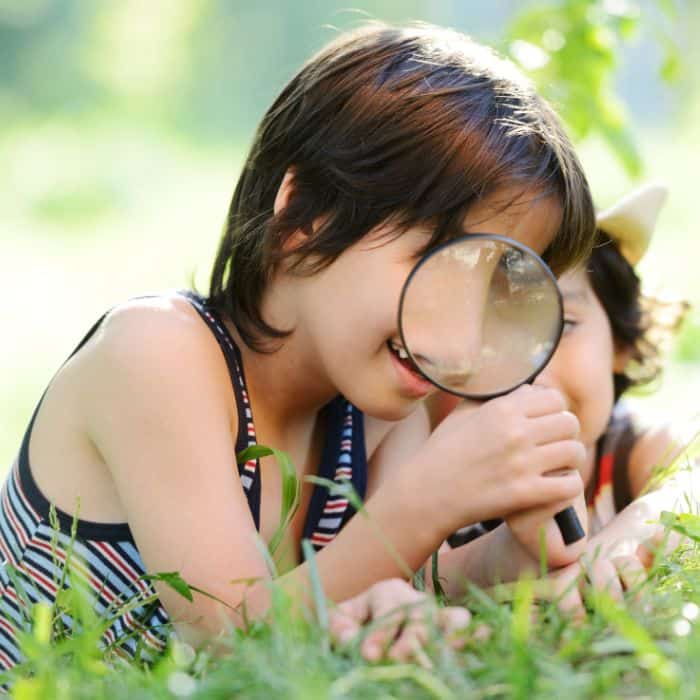 A child exploring nature using a magnifying glass.