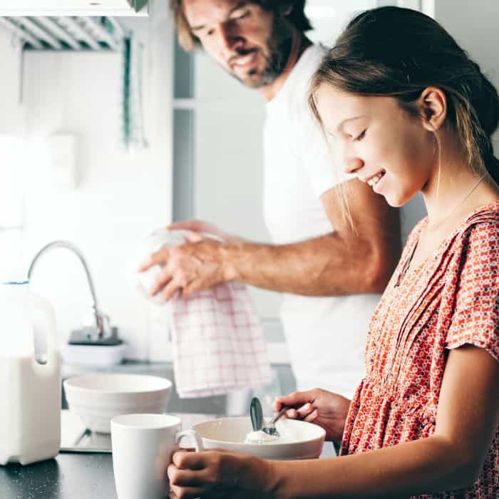 A father and daughter honor their bond while preparing a hot beverage in a bright kitchen setting, reminiscent of the "honor your father and mother" Bible verse.