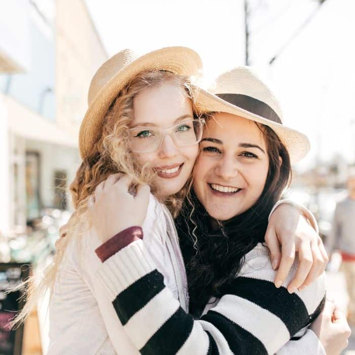 Two girls wearing hats hugging each other.