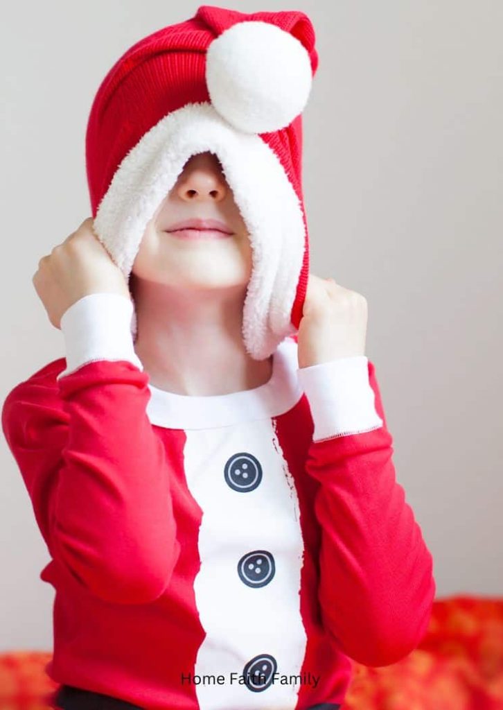 Small child hiding under a Santa hat.