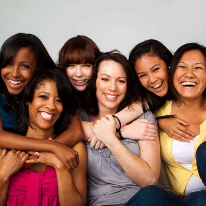 A group of diverse women hugging and smiling together.