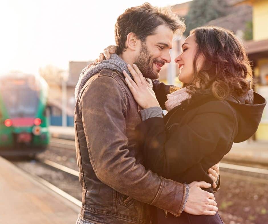 A couple embracing at a train station.