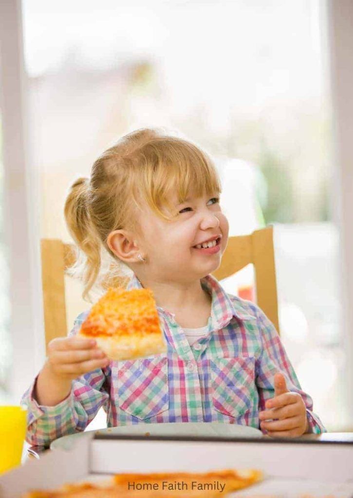 A little girl eating cheese pizza with her family for meat-free Lent Friday.