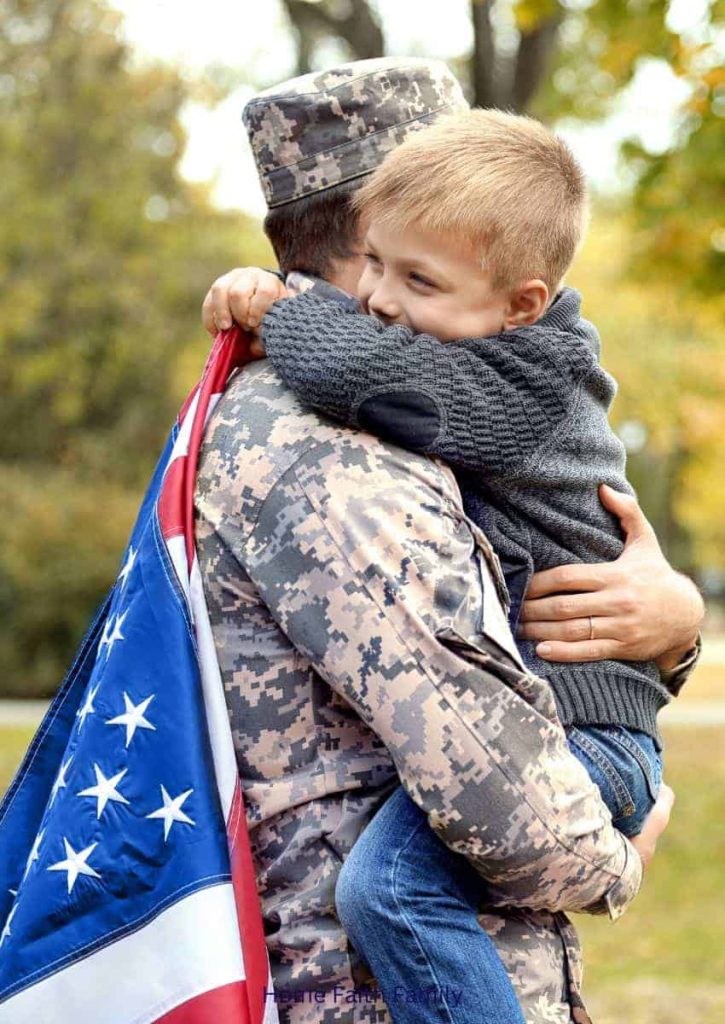 A little boy is hugging his military soldier father. Both are draped in am American flag.