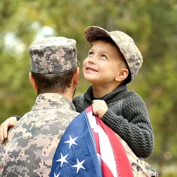 An American soldier with a little boy holding an American flag in his arms.