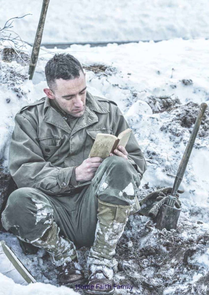 A soldier praying and reading the Bible in the snow.