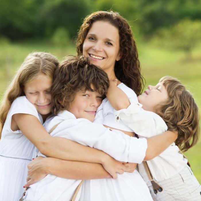 A mother is being hugged by her children.
