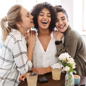 A group of women huddled together laughing and smiling.