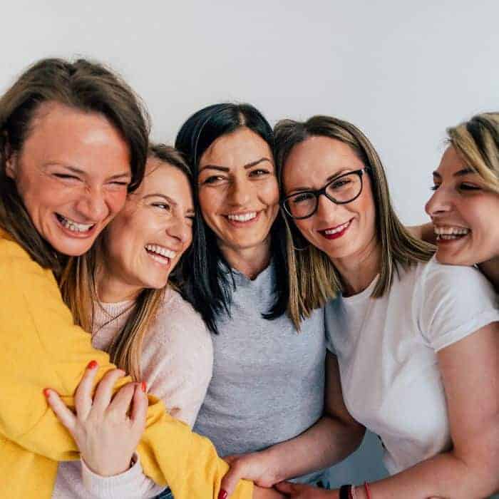 A group of women huddled together in a hug, smiling and laughing.