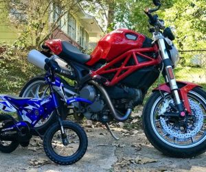 toddler motorcycle next to Ducati Monster red motorcycle.
