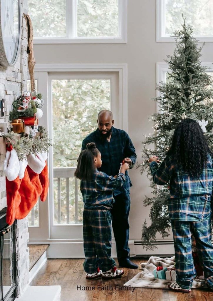 A family wearing matching pajamas and standing in the living room. They're decorating the Christmas tree.