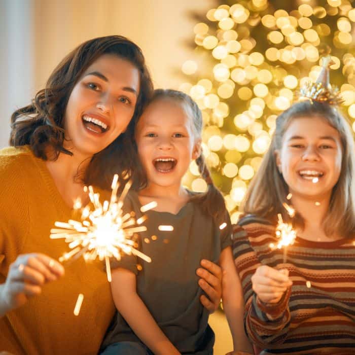 A mother with her two daughters. They have sparklers and are celebrating New Years.