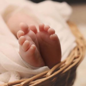 Tiny baby feet peeking out from a soft blanket in a cozy basket, immortalized in poems for stillborn babies.