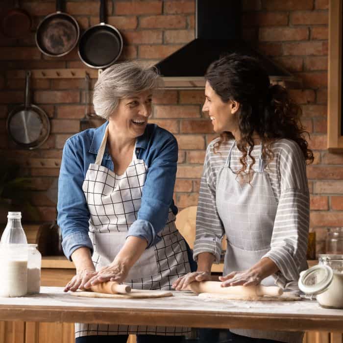 An older woman and her adult daughter are baking in the kitchen together.