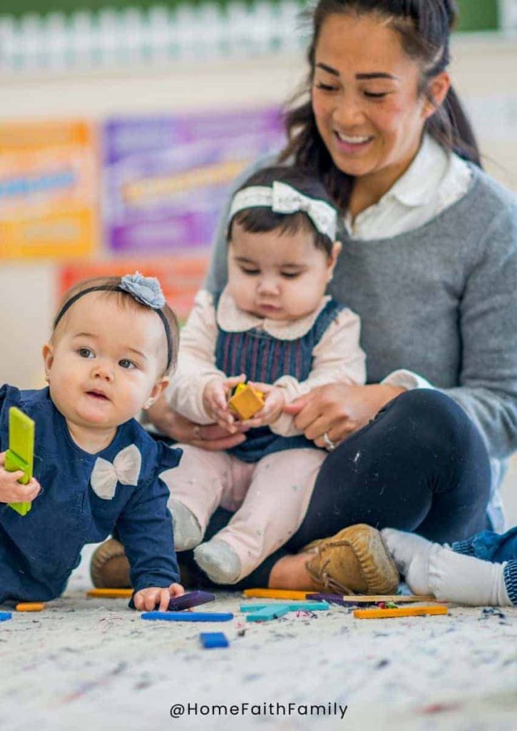 A daycare worker with children sitting on her lap and on the rug around her.